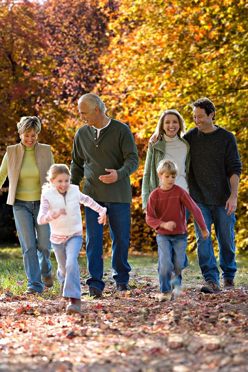 Family walking through autumn forest with colourful leaves