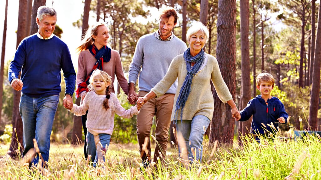 Family walking in forest holding hands and smiling