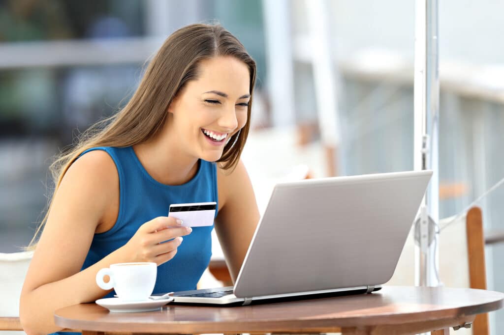 Smiling woman shopping online with a credit card and laptop